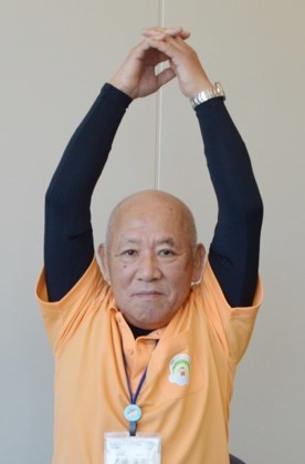 肘を伸ばしたままゆっくりと頭上に上げて伸ばす体操の写真