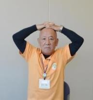 手の平を頭に乗せる体操の写真