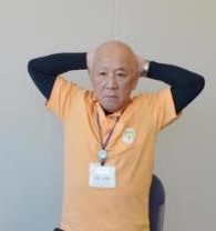 手の平を頭の後ろにまわして肘を開く体操の写真