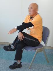 足を組み反対の手で膝を押さえる体操の写真