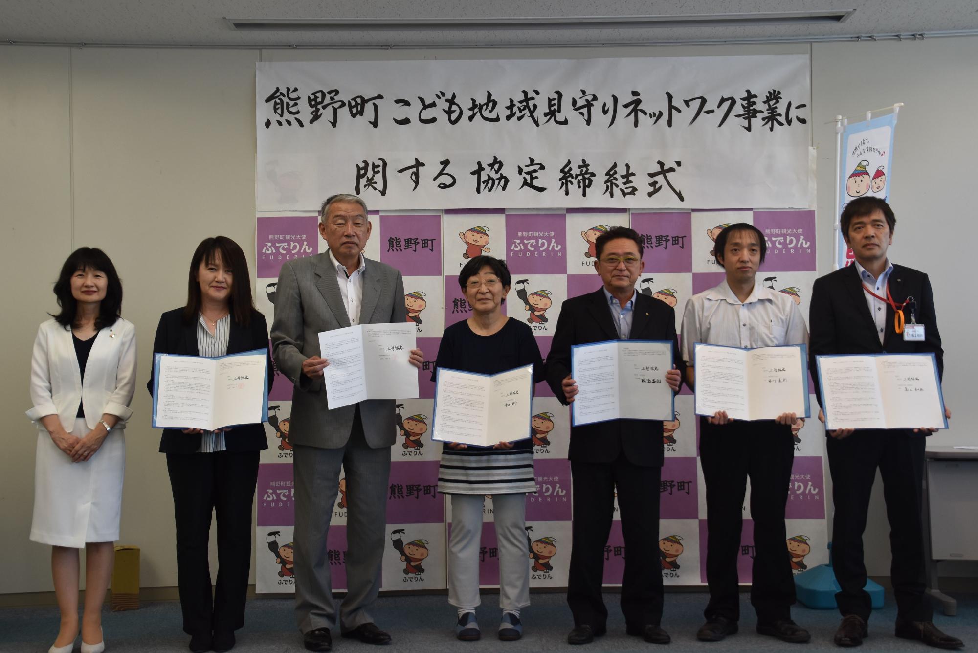 協定締結式で熊野町長といっしょに記念撮影に臨む協定書を手に持った事業所の代表者たちの写真