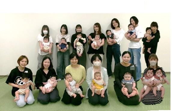 たくさんの女性たちが赤ちゃんを抱っこしながら並んで笑っている写真
