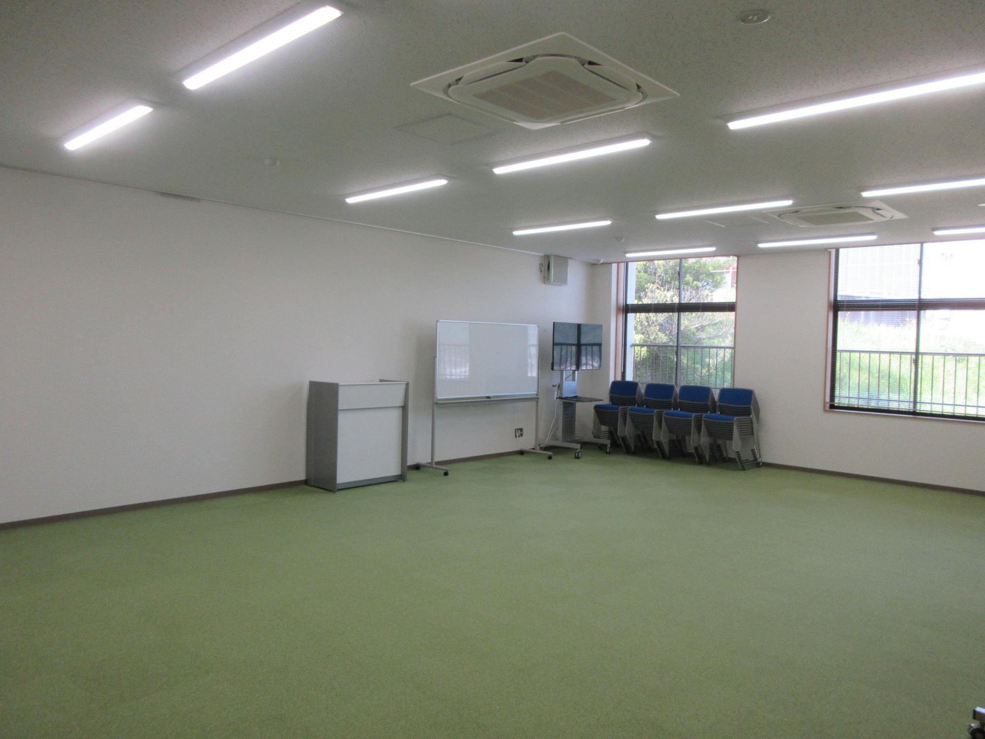 室内の隅に椅子やホワイトボードが置かれている広い部屋の写真