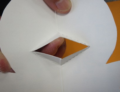 キャラクターの形に切られた紙に開けられた穴から指を通している写真