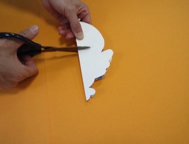 キャラクターの形に切られた紙にハサミを入れている写真