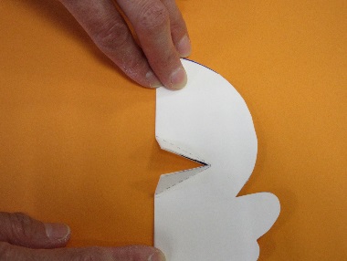 キャラクターの形に切られた紙に引かれた線に沿って折り目を入れている写真