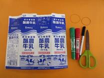 牛乳パック、輪ゴム、マジック、ハサミが並んで置かれている写真