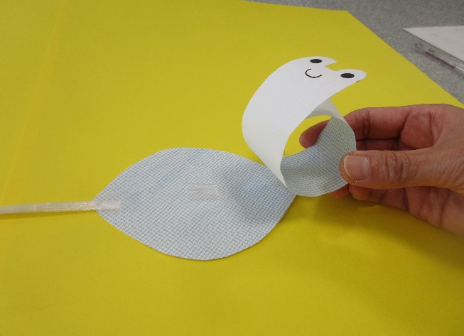 顔の描かれた細長い紙が紐の付いた紙と隣り合っている写真