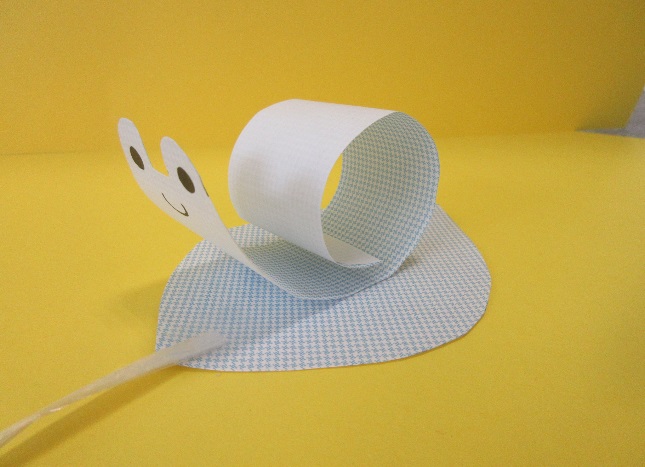 顔の描かれた細長い紙が紐の付いた紙に乗せられている写真