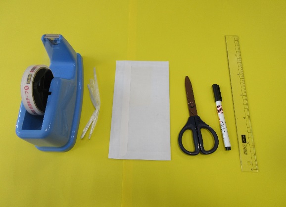 セロテープ、紐、白い紙、ハサミ、マジック、定規が並んで置かれている写真