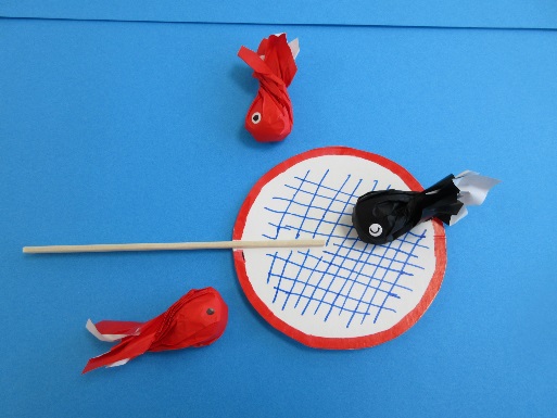 紙で作られた金魚すくいのポイの上に紙で作られた金魚が置かれている写真