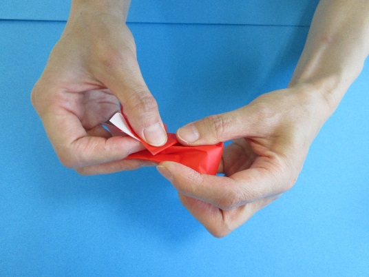 赤い折り紙を持ちながら折っている写真