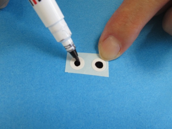 小さい紙に描かれた白い円の中に黒い丸を描いている写真