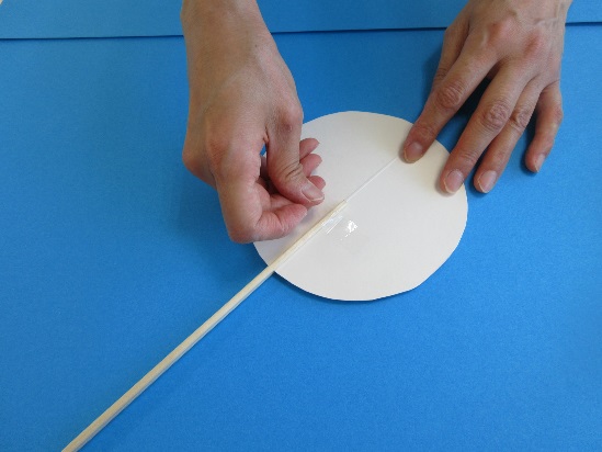 丸く切られた紙にセロテープで割りばしを固定している写真