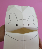 開かれた牛乳パックの内側に動物の顔を描いている写真