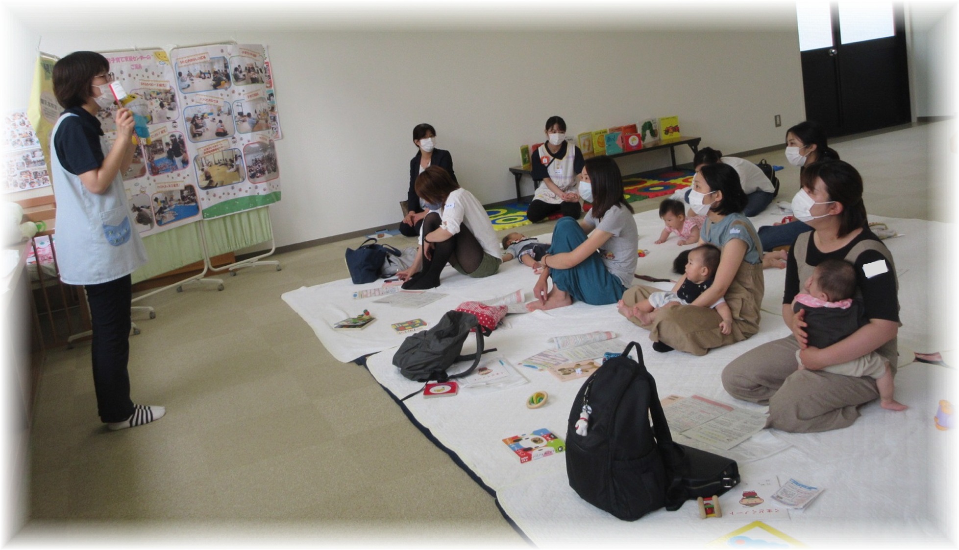 保護者と赤ちゃん達の前に立って話す女性の写真
