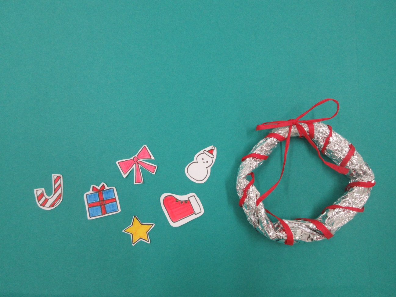 星やプレゼントの箱が描かれた紙と輪っか型のアルミホイルが並べられている写真