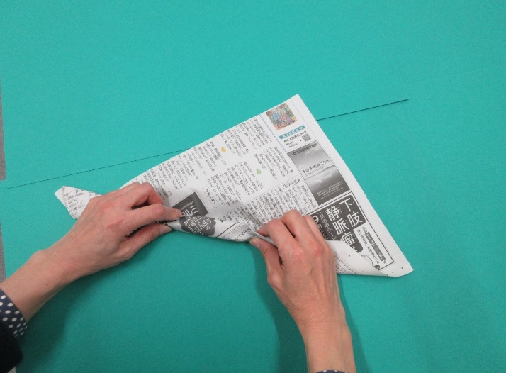 新聞紙を巻きながら丸めている写真