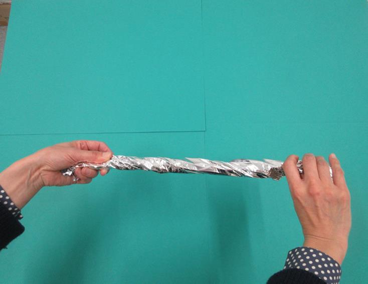 棒状にしたアルミホイルを持っている写真