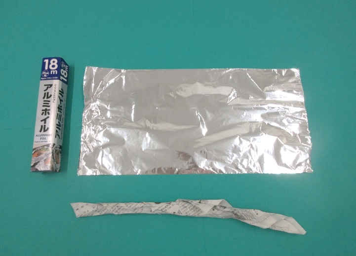 広げられたアルミホイルと棒状の新聞紙が並べられている写真