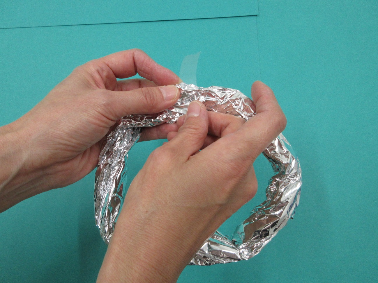 輪っか型のアルミホイルにセロテープを貼り付けている写真