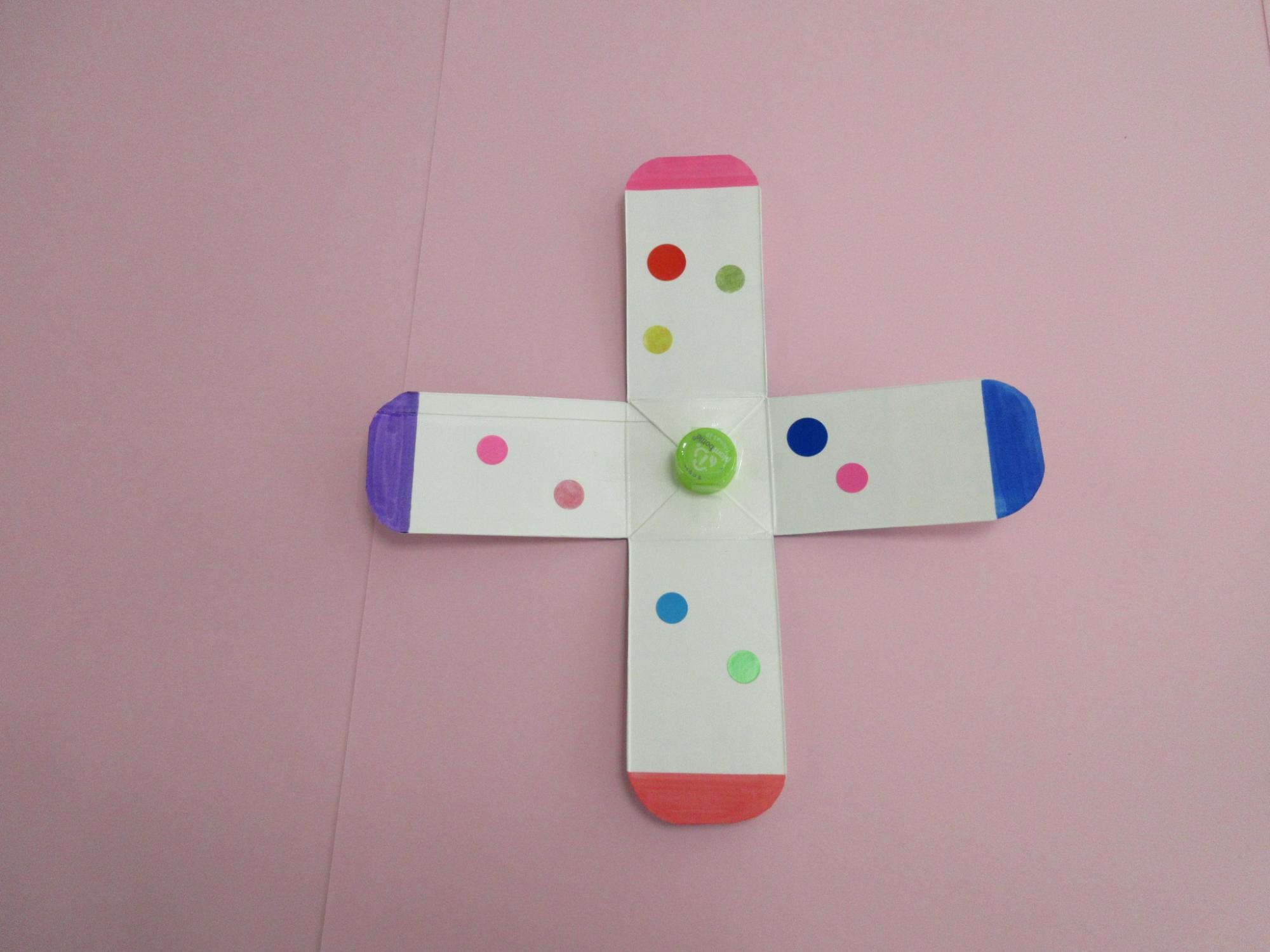 プラスの形に切り抜かれた紙にシールが貼られている写真