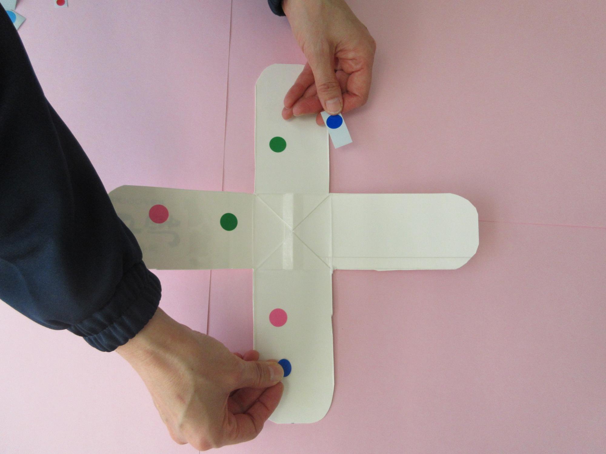 十字に広げられた牛乳パックにシールを貼っている写真