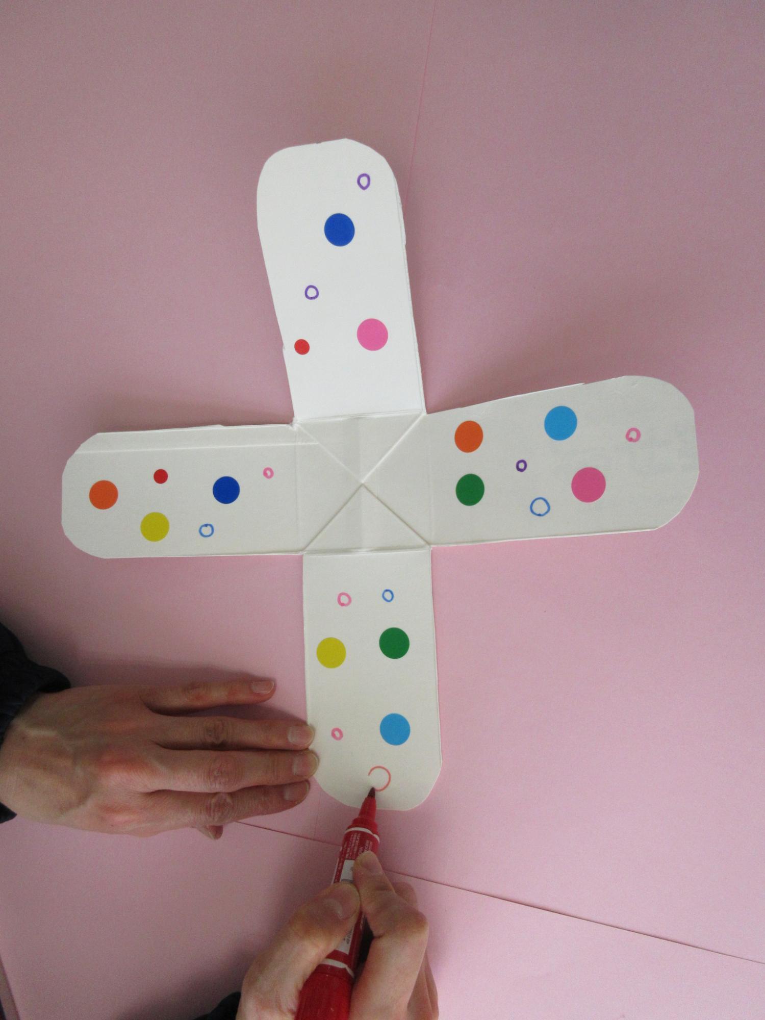 十字に開かれた牛乳パックの内側に水玉模様を描いている写真