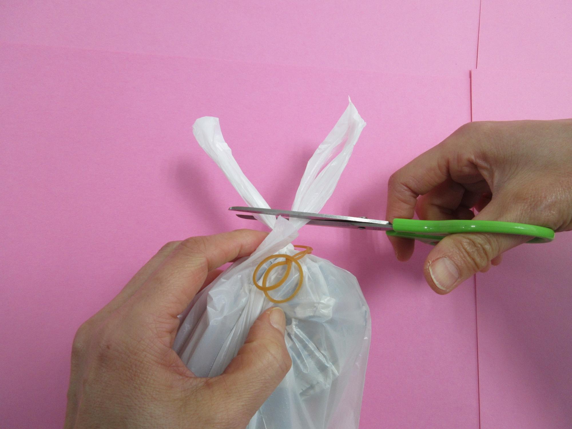 レジ袋の手持ち部分にハサミを入れている写真