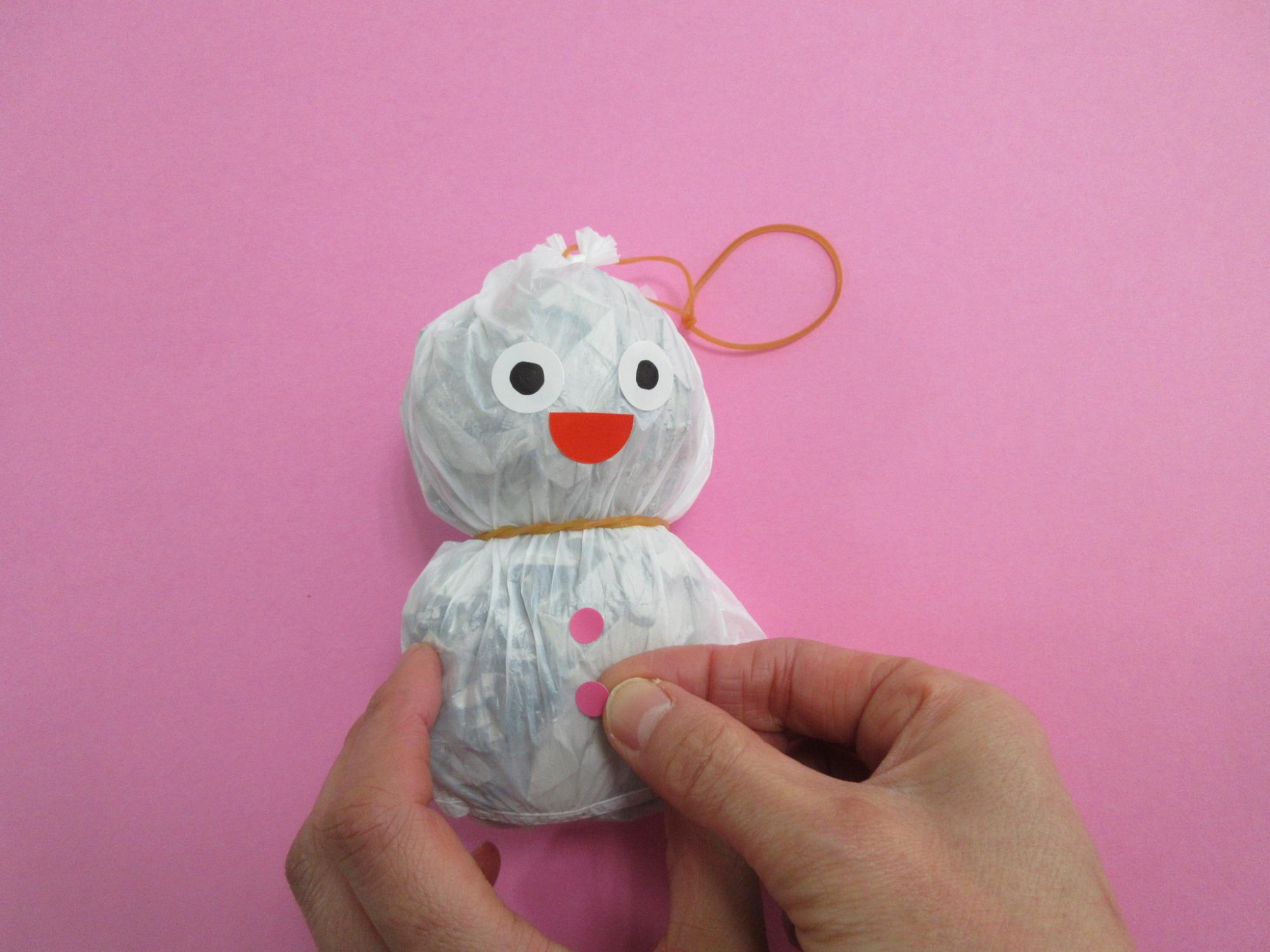 輪ゴムを取り付けられたレジ袋にピンクの紙を貼っている写真