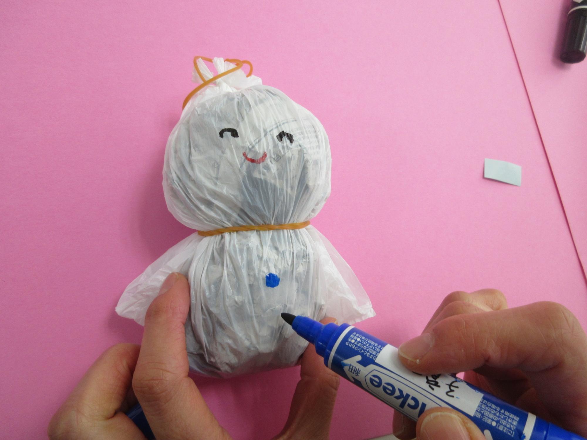 輪ゴムを取り付けられたレジ袋に笑顔を描いている写真