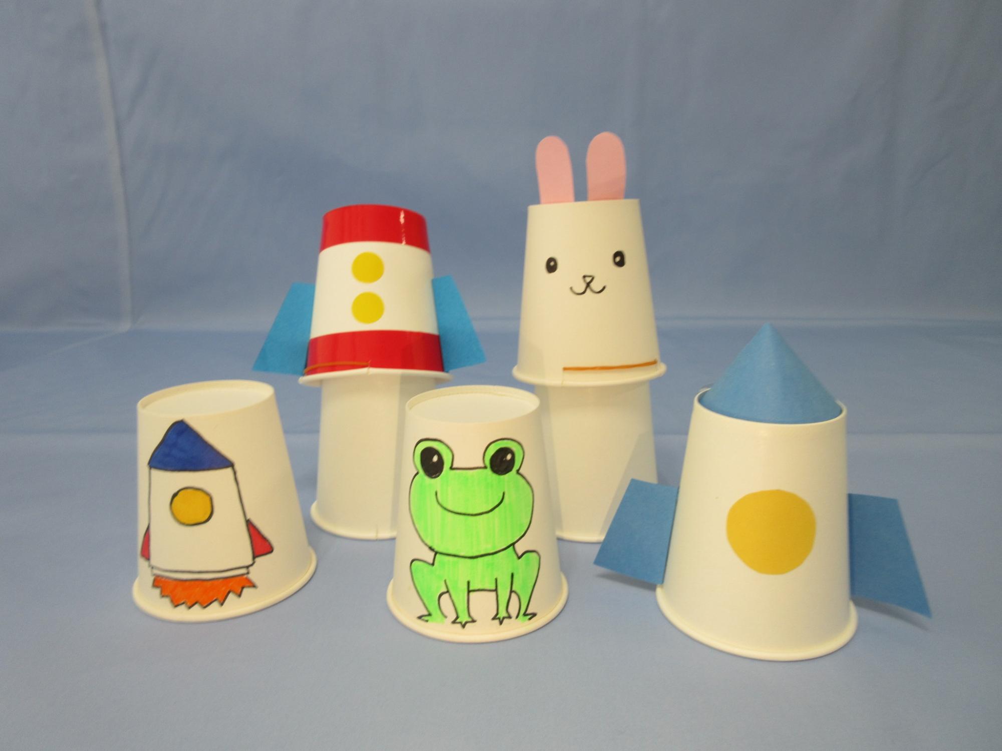 ロケットや動物が描かれた紙コップが並べられている写真