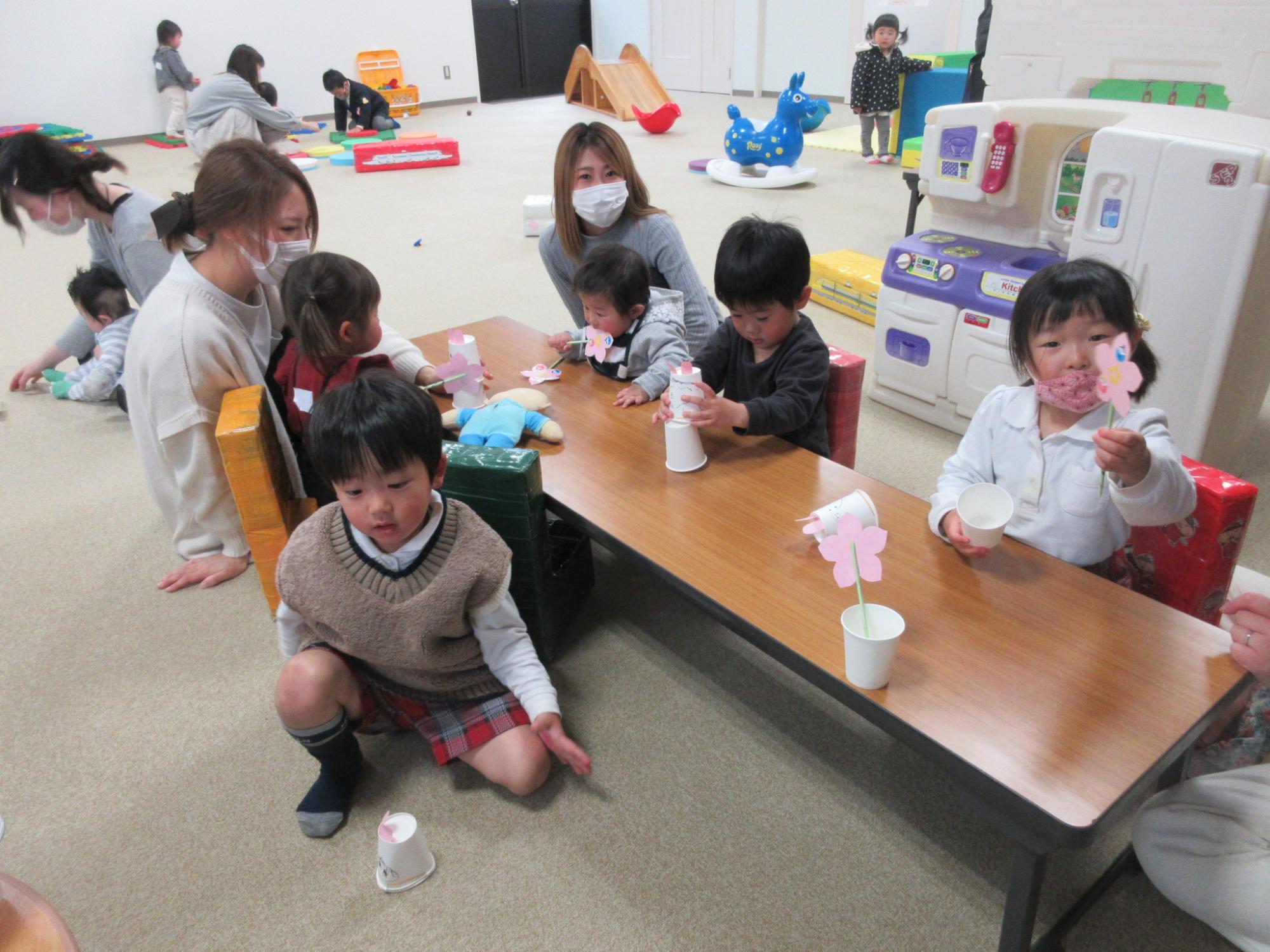 背の低いテーブルで工作をしている子供たちの写真