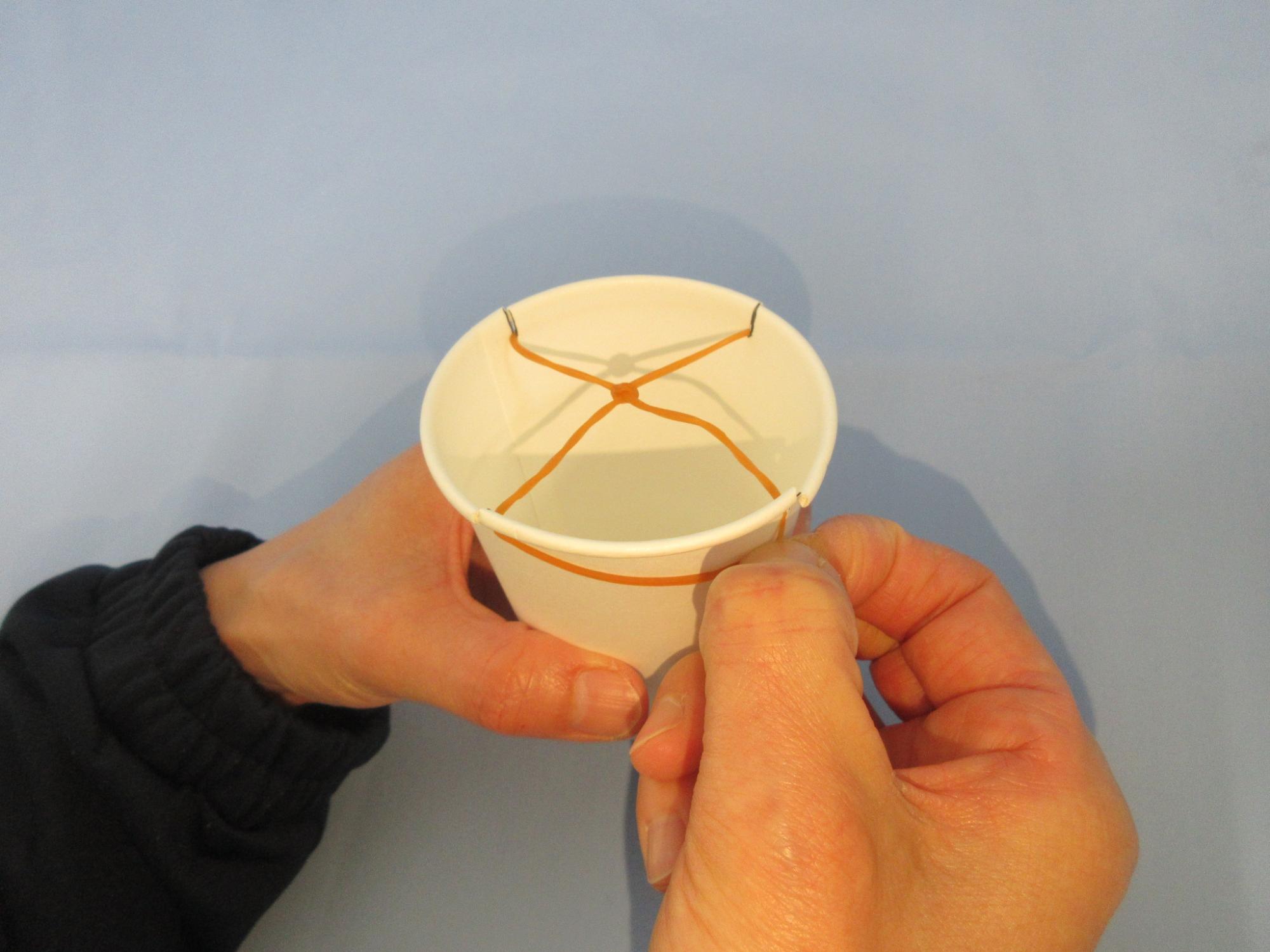 紙コップのふちにある切れ込みに輪ゴムをかけている写真