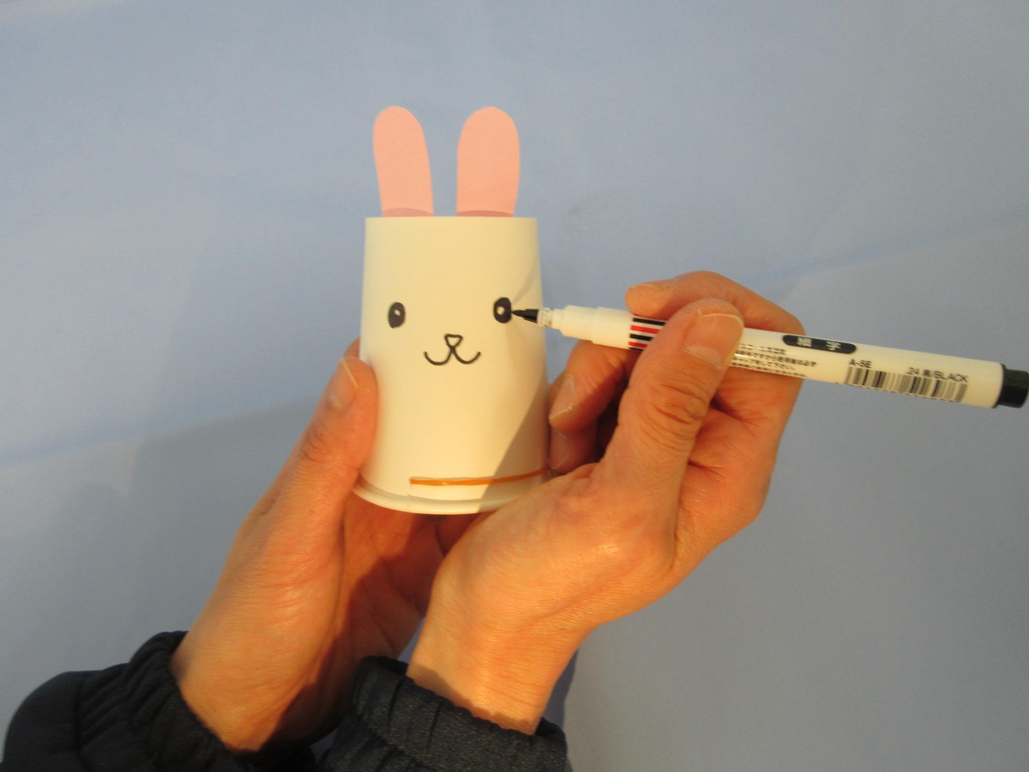 紙コップにマジックでウサギの顔を描いている写真