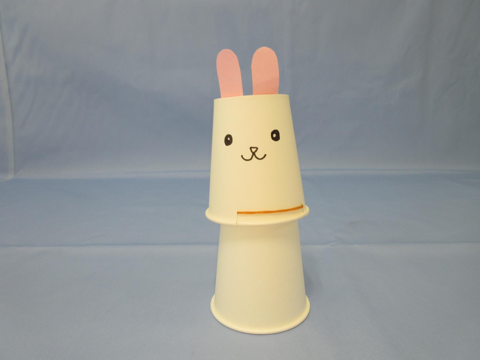 ウサギの顔が描かれた紙コップの下にもう1つの紙コップが置かれている写真