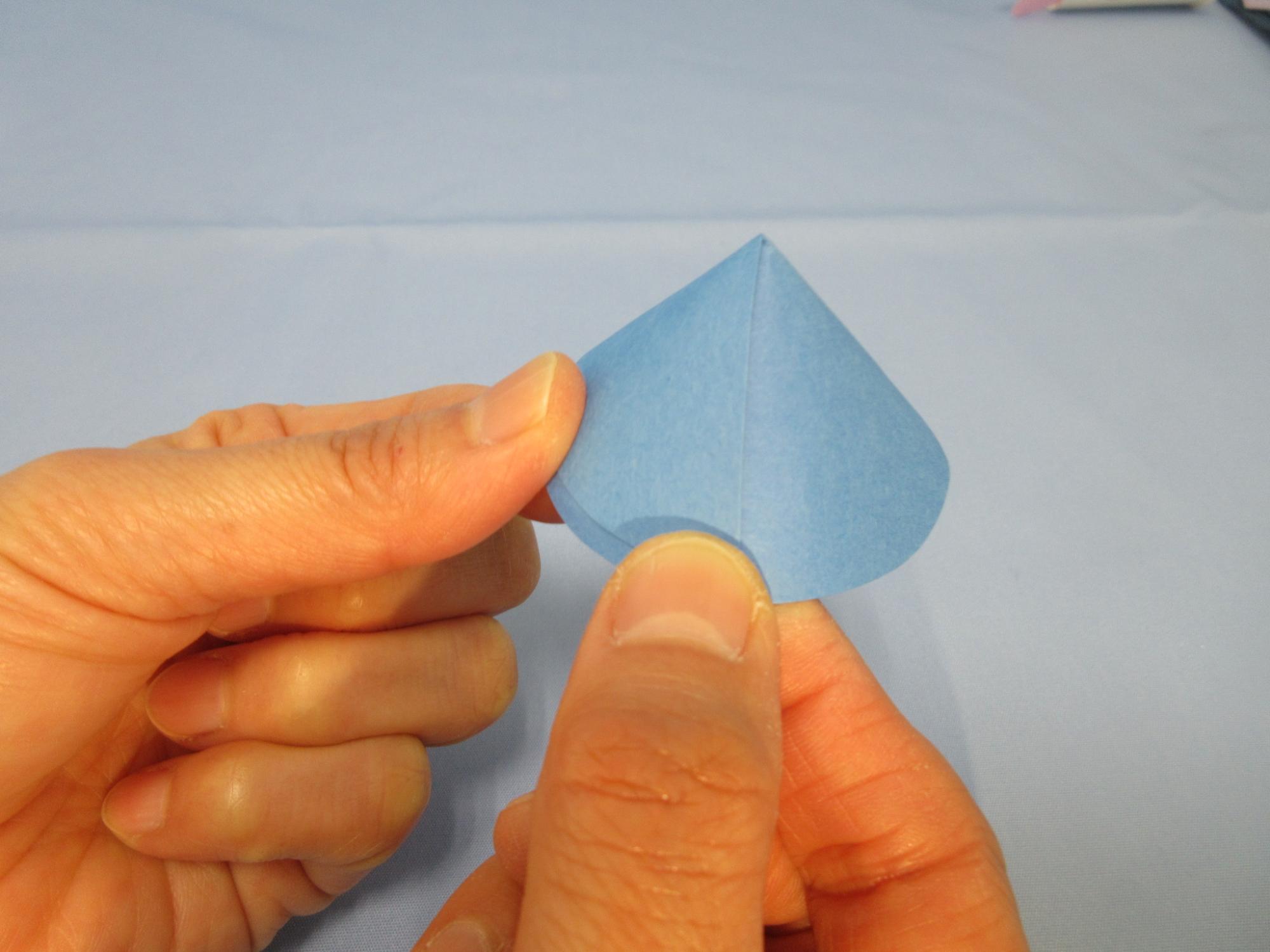 三角錐の形をした青い紙を持っている写真