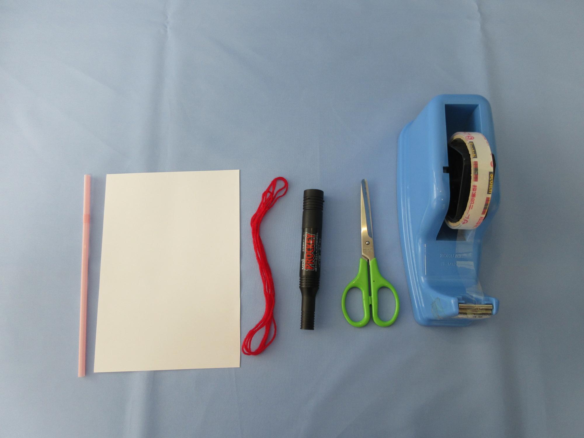 ストロー、紙、赤い紐、マジック、ハサミ、セロテープが並べられている写真