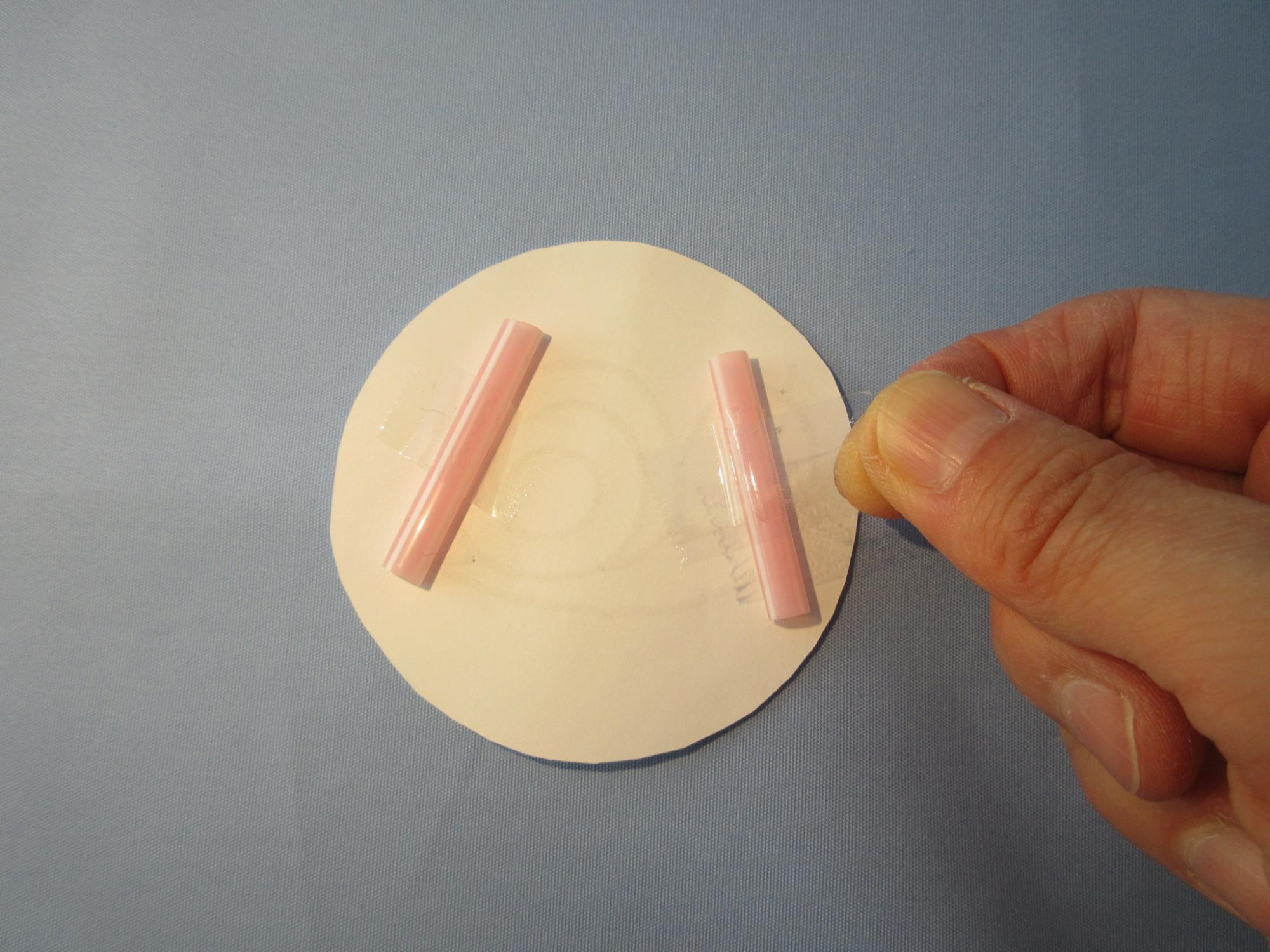 丸い紙に短いストロー2本をセロテープで貼っている写真