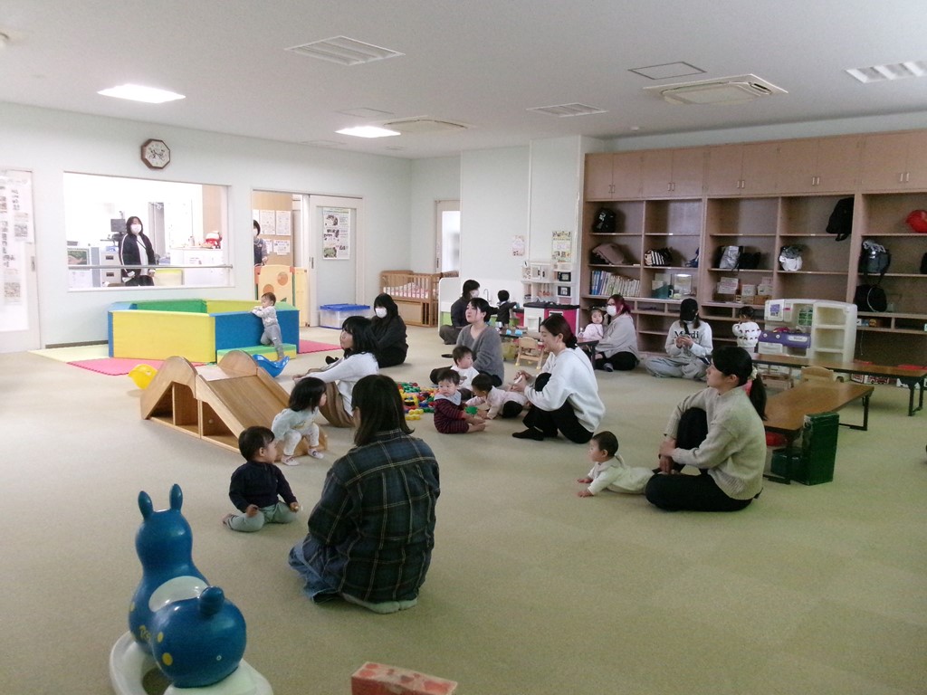 参加者が子どもの遊びを見守りながら話を聞いている写真