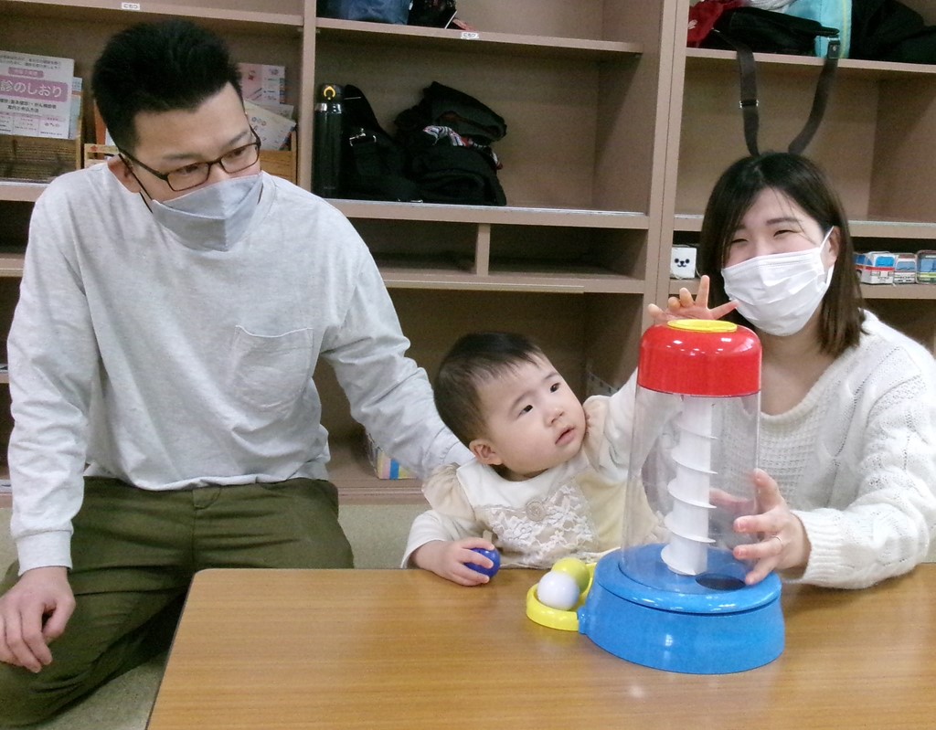 おもちゃで遊ぶ父と母と子どもの写真
