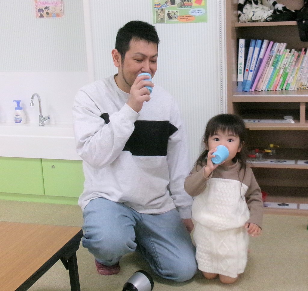 ままごとで飲み物を飲むまねをする子どもとお父さん