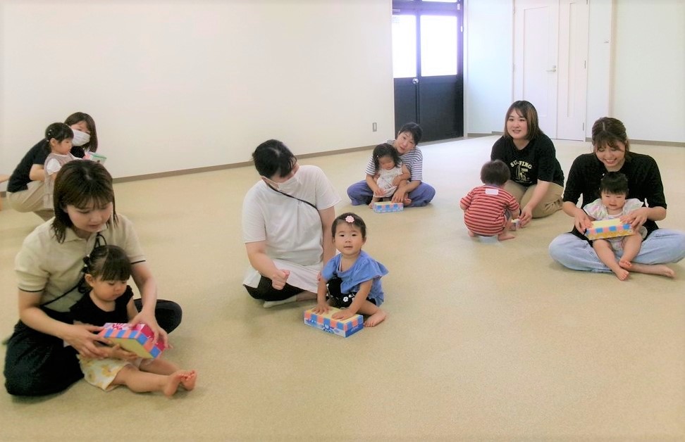 楽器作って演奏する子どもを膝に座らせている様子
