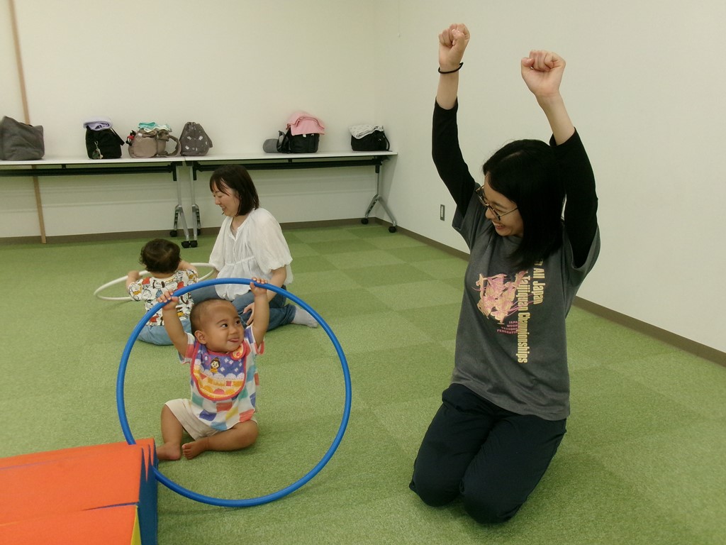 6月のアタッチメントジムでフラフープを持って体を伸ばす子どもと母の様子