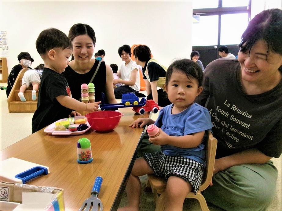 多目的室のおもちゃで一緒に遊ぶ2組の親子の様子