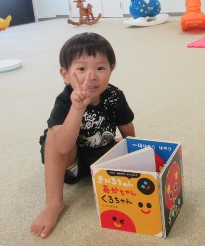 絵本で四角を作ってピースサインをする男子