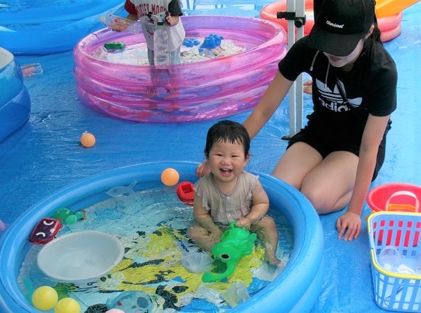 8月子ども用プールに入り笑顔の子どもの様子