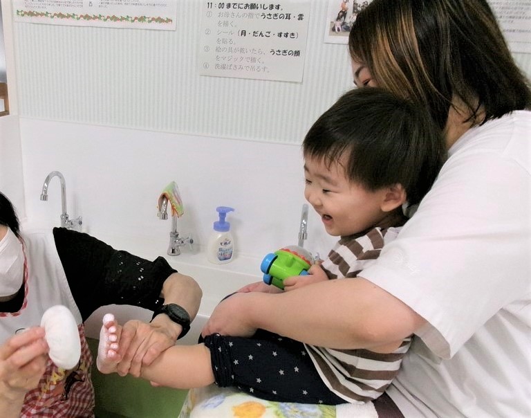 お月見うさぎの作品で、母に抱かれた子どもが足形を取っている様子