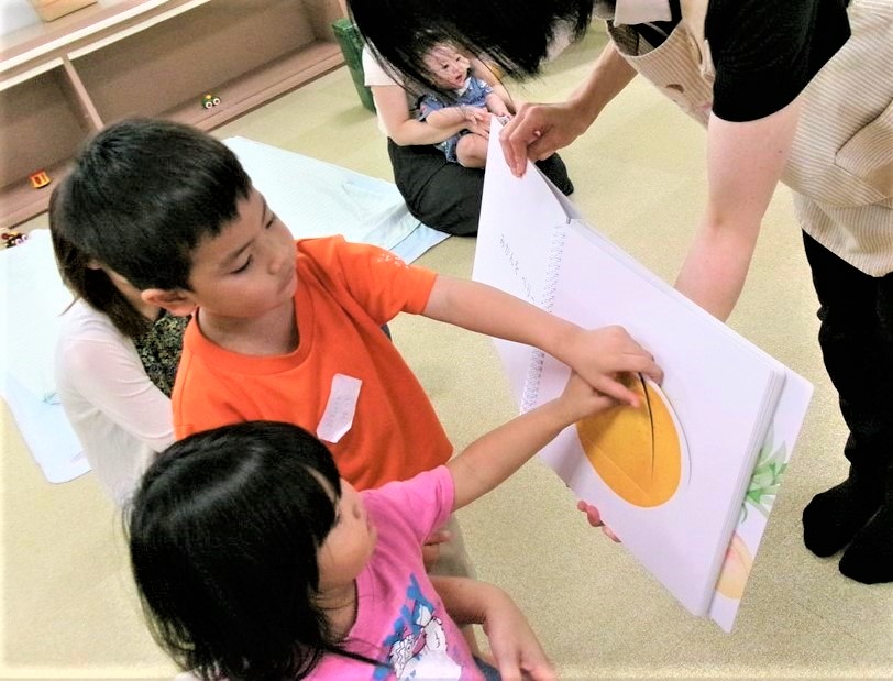 保育士としかけ絵本で遊ぶ男の子と女の子