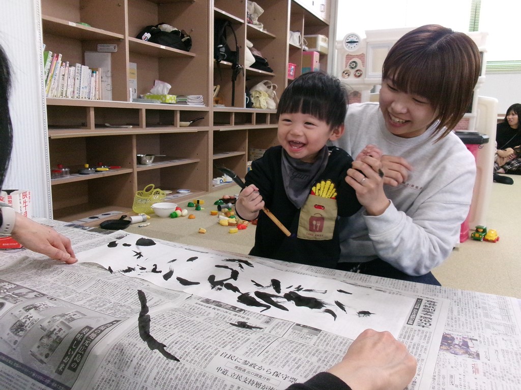 筆を使って作品をつくる笑顔の子どもの写真